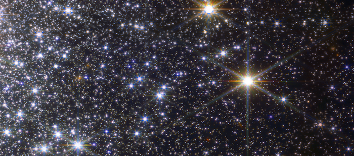 Two bright stars and many other fainter ones, spreading out across space from the left side of the image