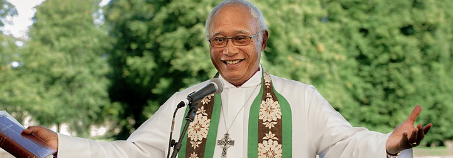 A man wearing clerical robes with arms outstretched